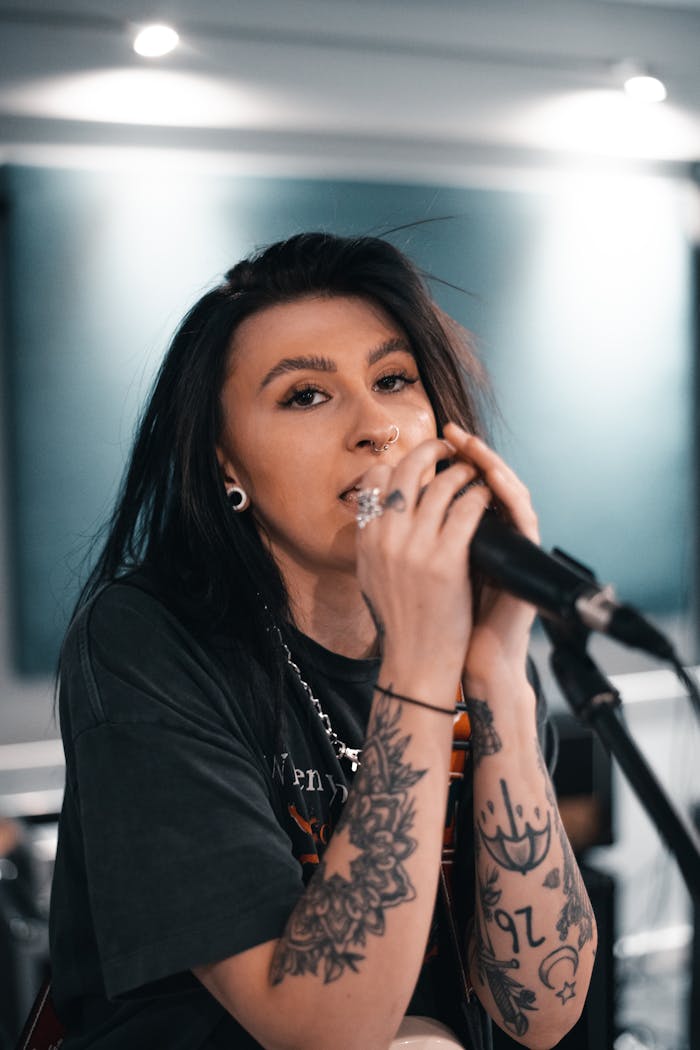 core-values Caucasian woman with tattoos singing passionately into a microphone during a live performance.